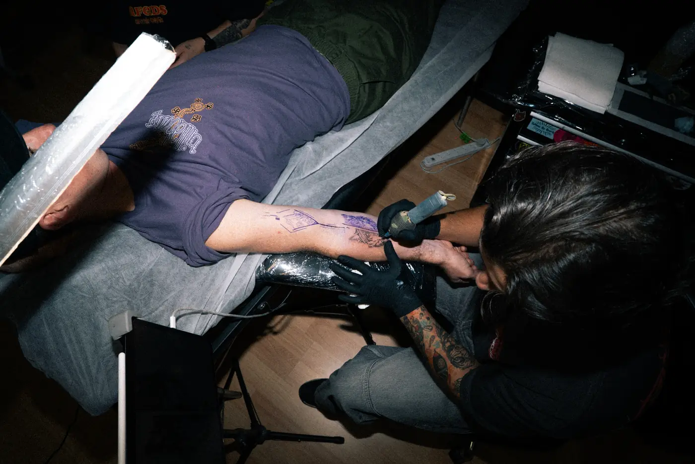 A Full Moon artist lining a forearm tattoo
