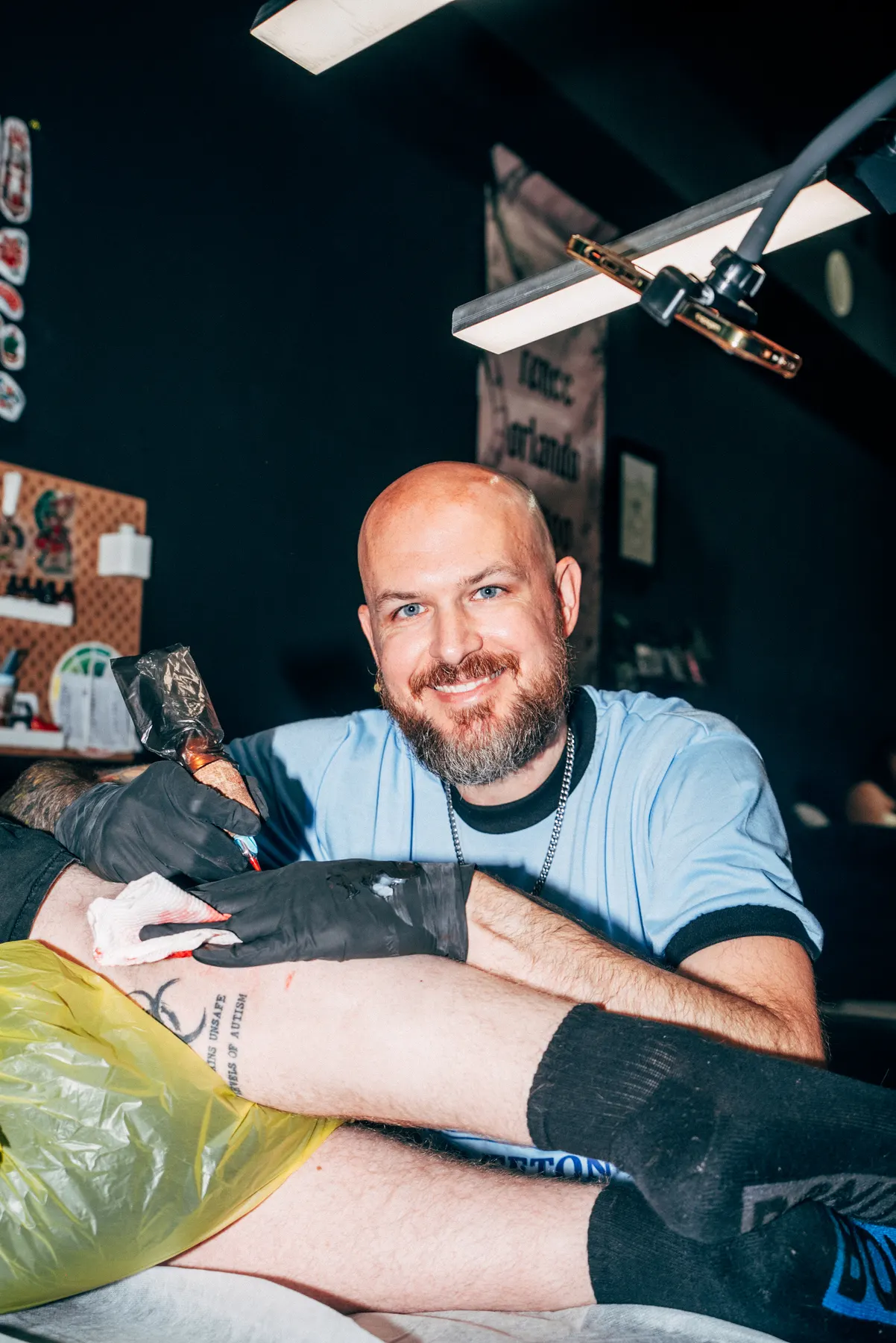 A Full Moon artist smiling while tattooing a leg piece