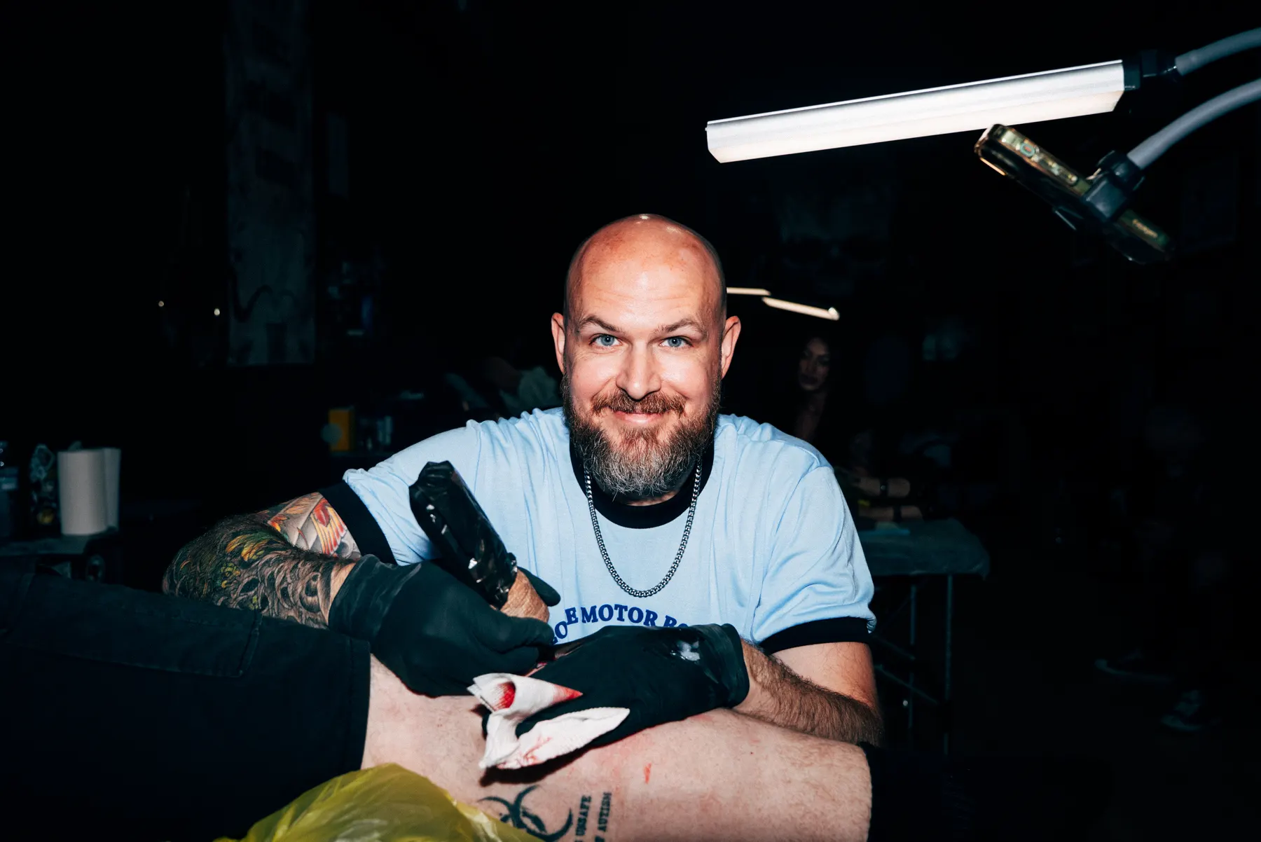 A Full Moon artist tattooing under the lamp in the Prahran parlour